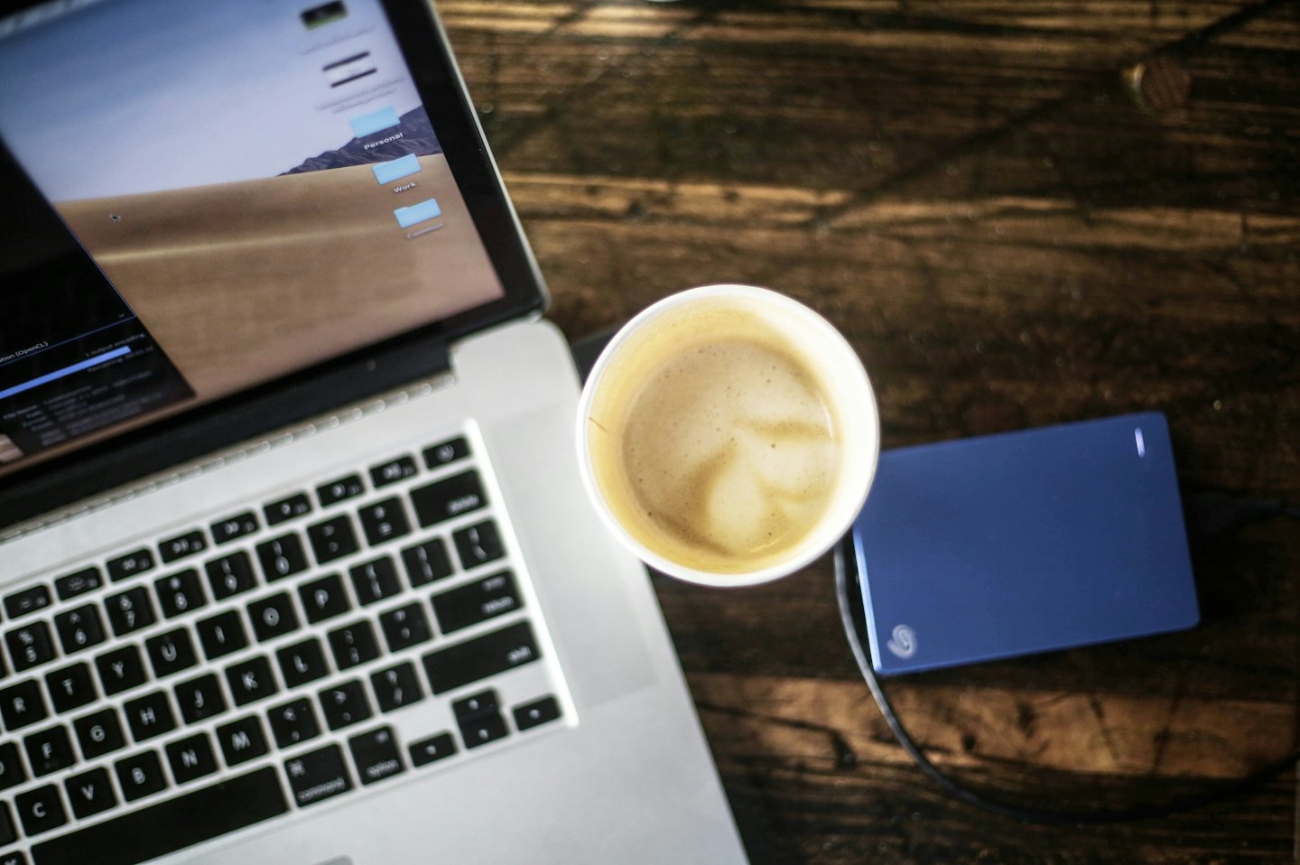 Laptop met werkmappen en latte art op een bureau.